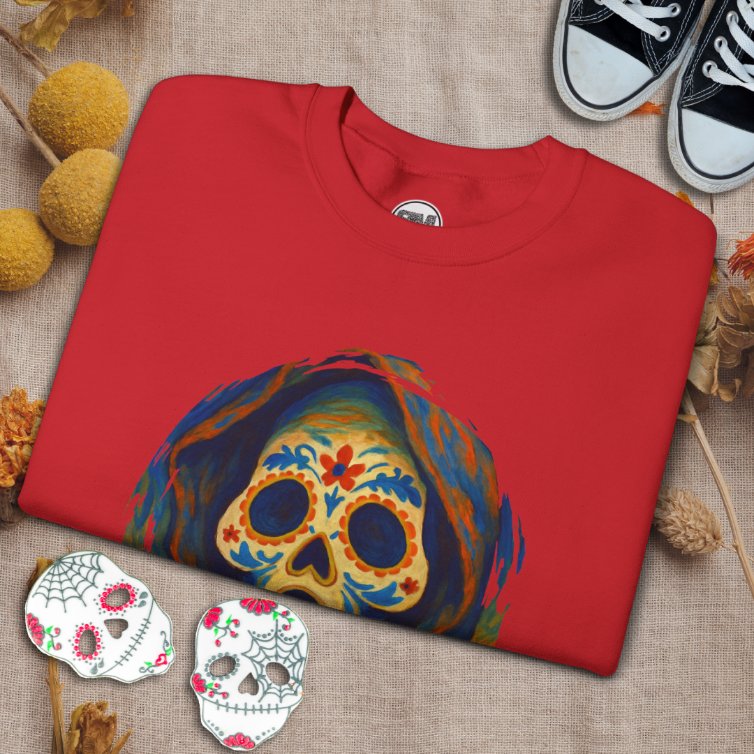 Folded red sweatshirt with a colorful ghost face sugar skull design on a textured surface.