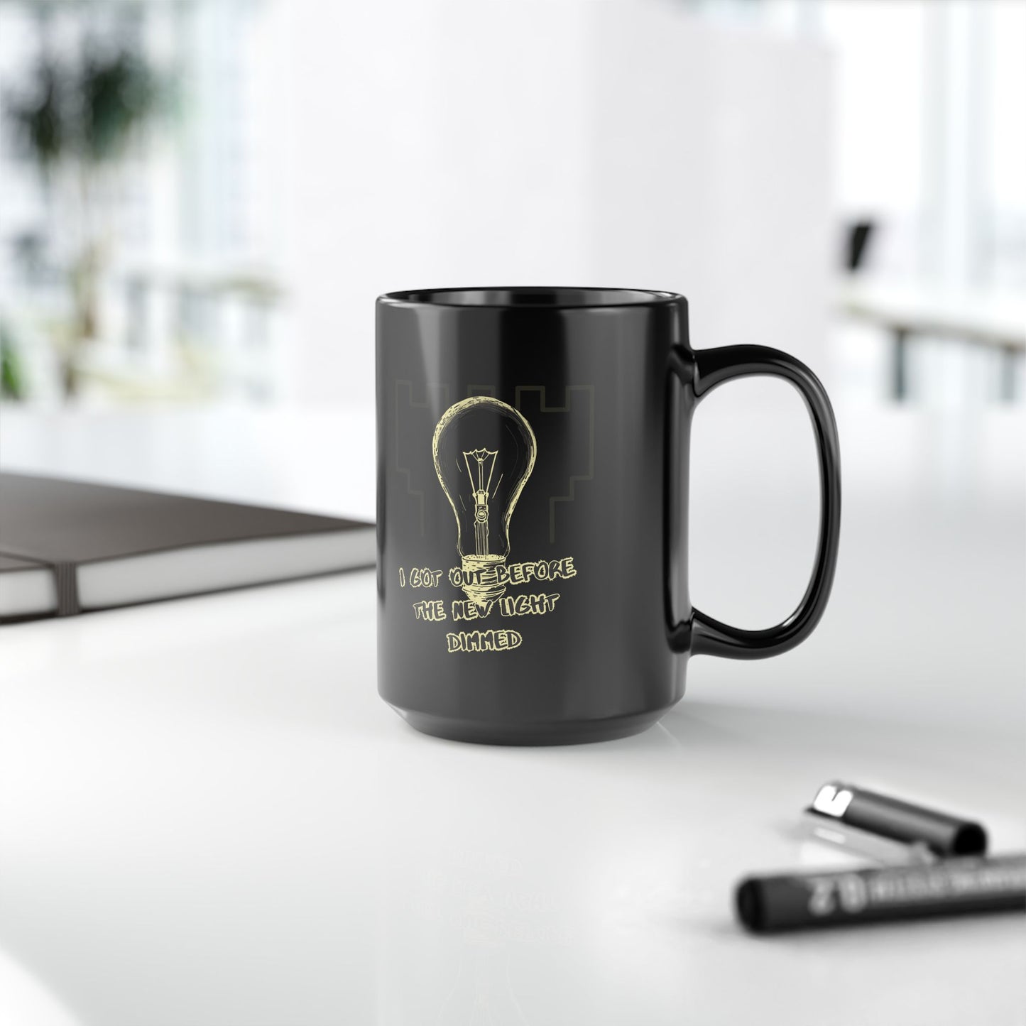 Glossy black ceramic mug with white text reading ‘I Got Out Before the Light Dimmed’ – ExJW survivor design.
