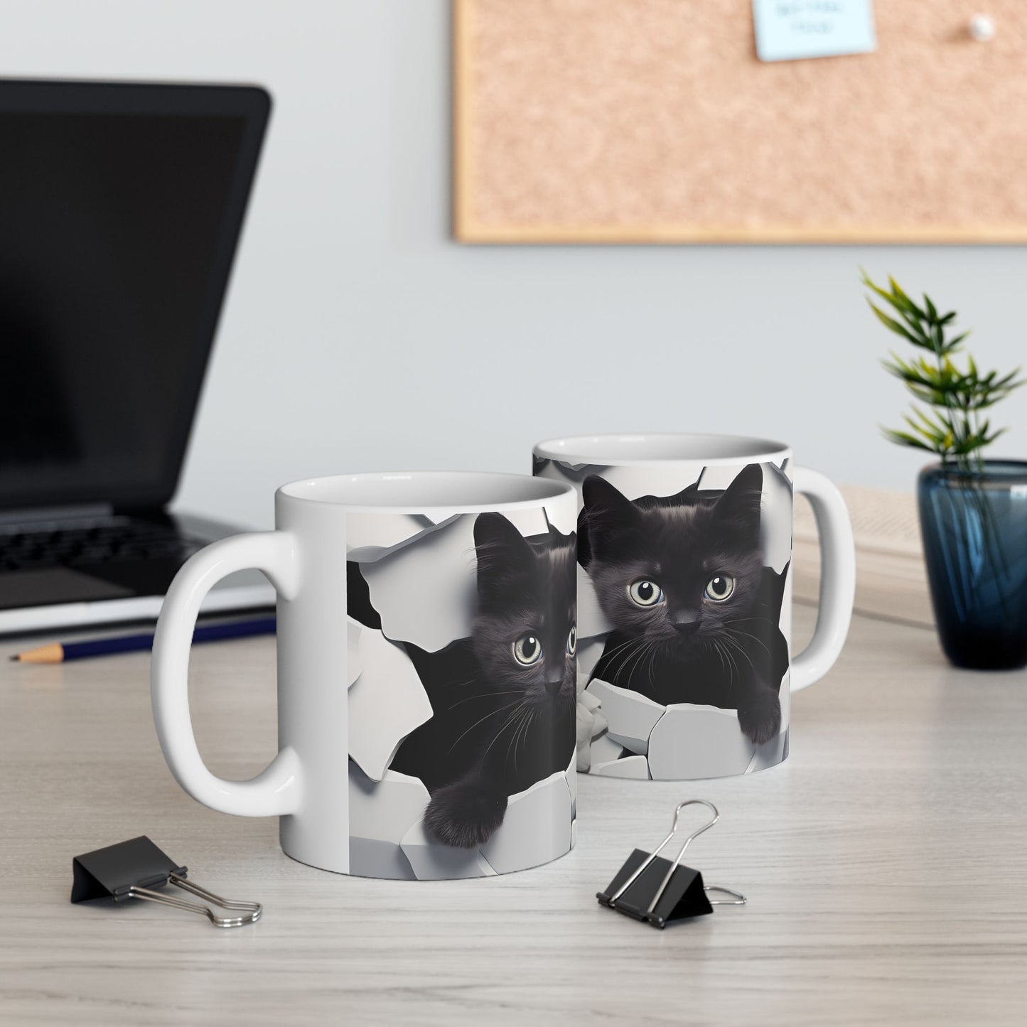 Two mugs with black cat designs on a desk with office supplies.
