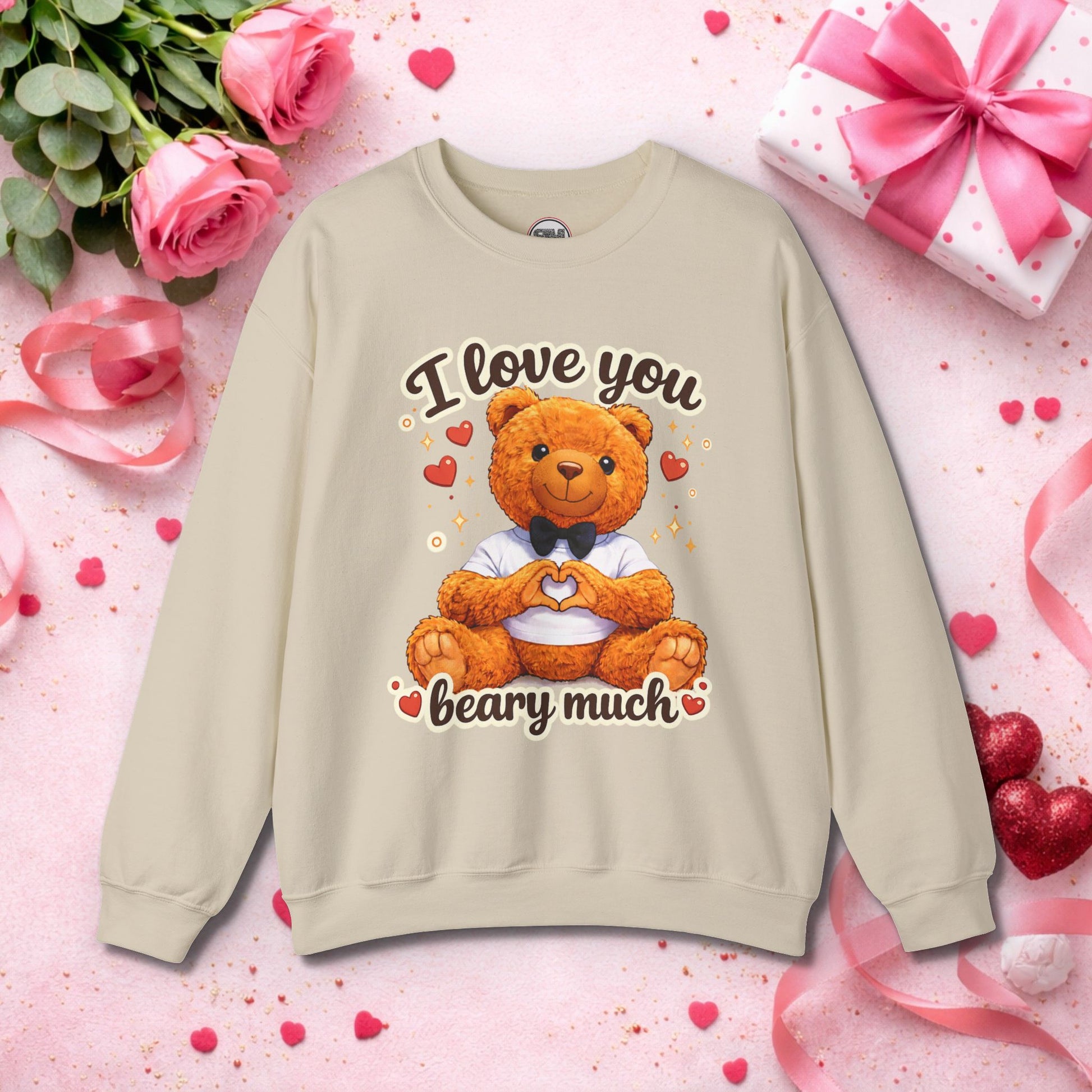 Cute brown teddy bear sitting on a cozy white sweatshirt, forming a heart shape with its paws, wearing a black bow tie and white shirt, surrounded by red hearts and sparkles with "I Love You Beary Much" pun text – perfect Valentine's Day gift sweatshirt for her