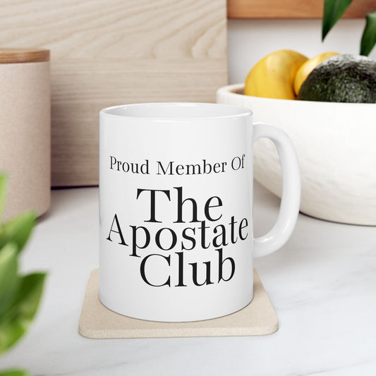 White mug with 'Proud Member Of The Apostate Club' text on a wooden coaster.
