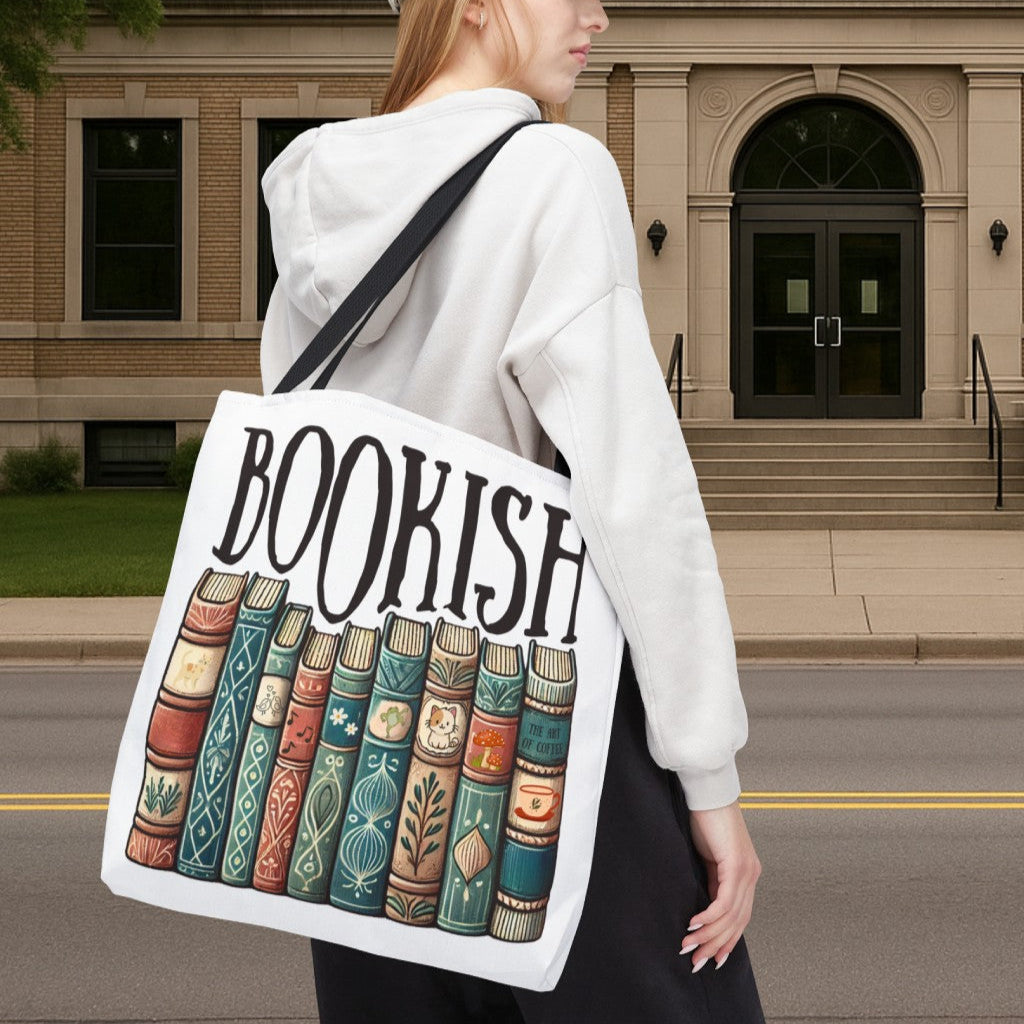 Person holding a tote bag with 'BOOKISH' and book illustrations in front of a building.