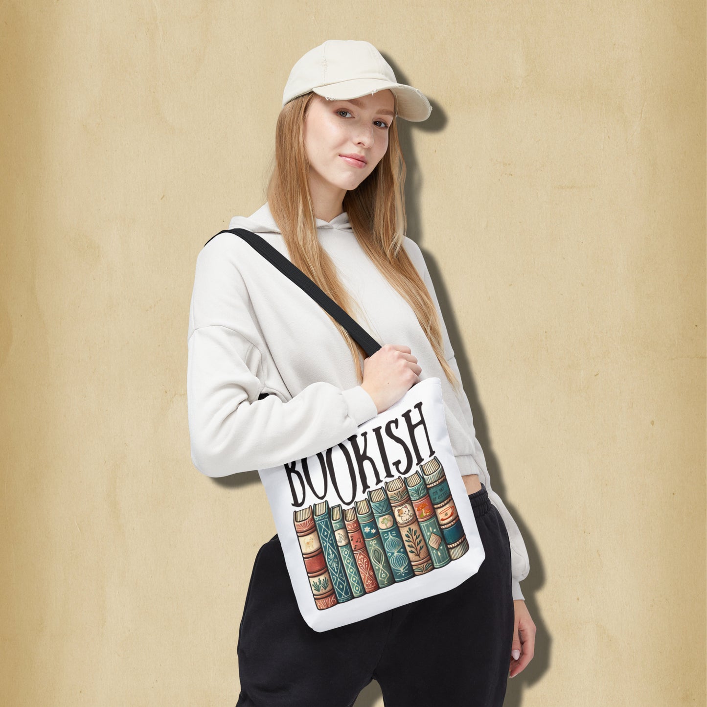 Person holding a white bag with 'BOOKISH' and book design against a beige background