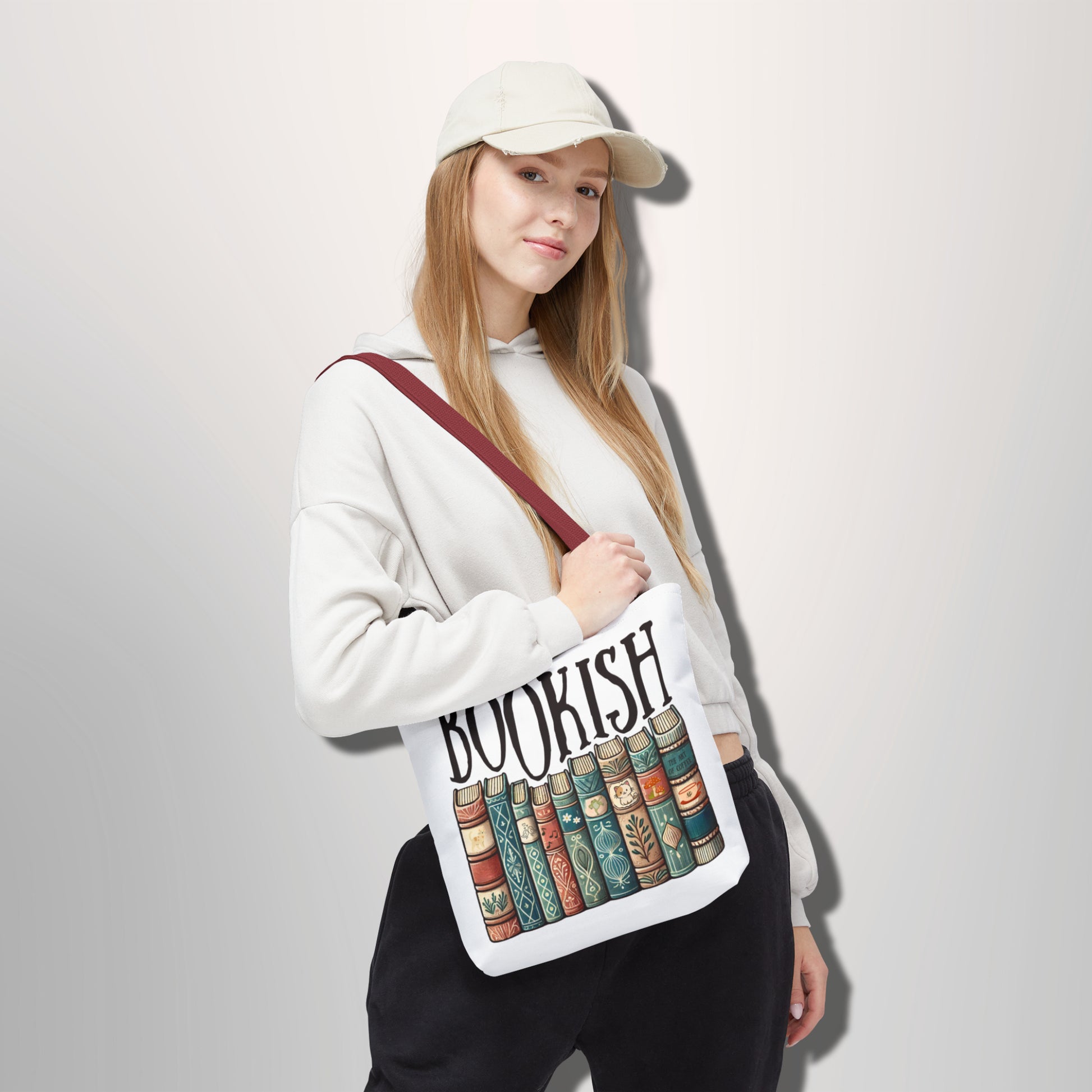 Person holding a tote bag with 'BOOKISH' and book design on a plain background