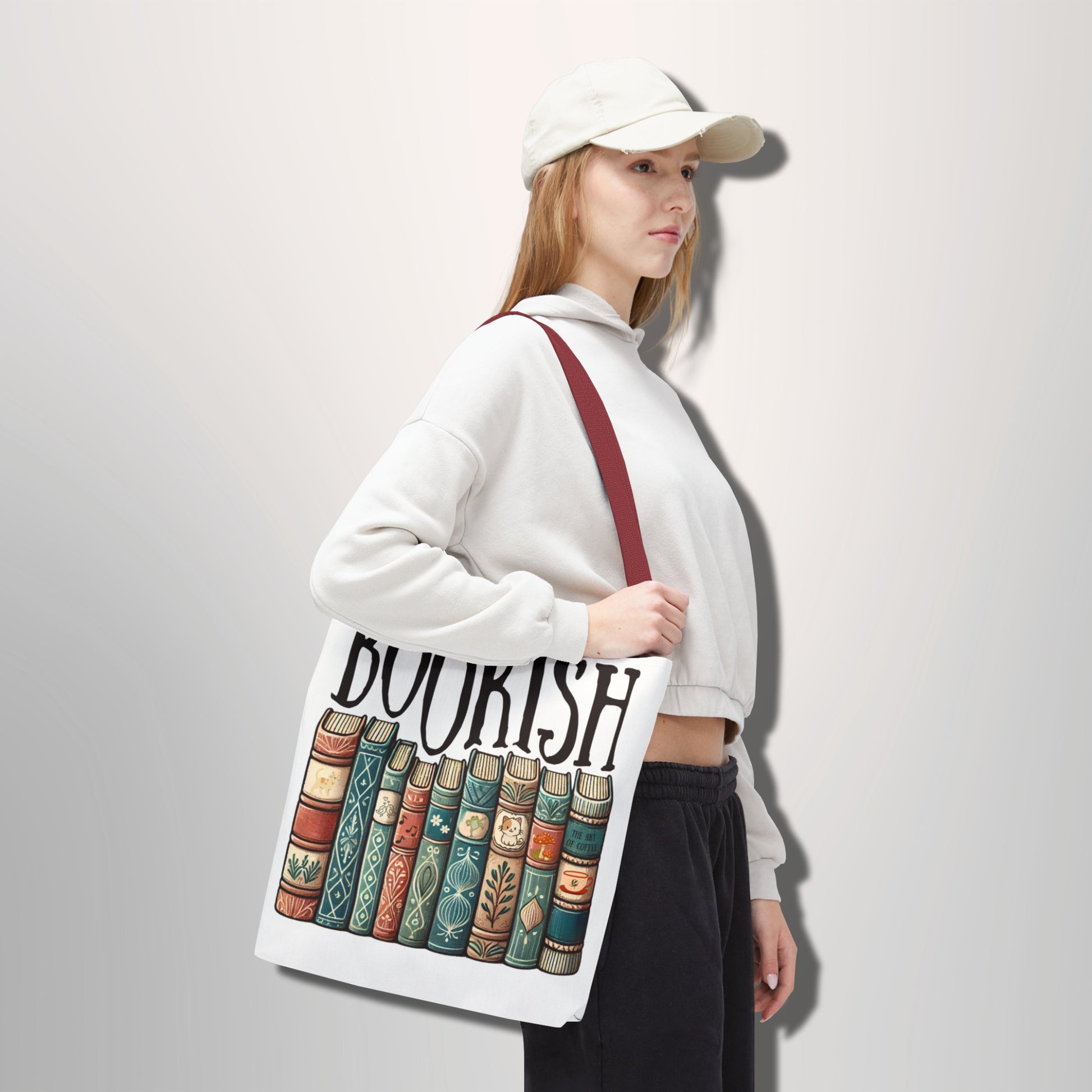 Person holding a tote bag with 'BOOKISH' and book design on a plain background