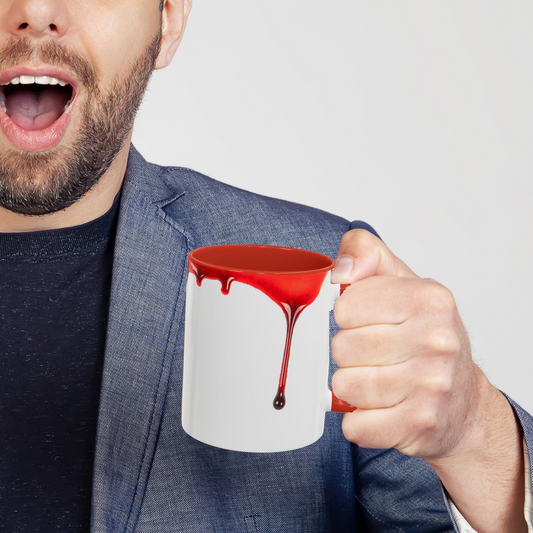 Man holding a mug with red blood dripping design against a plain background