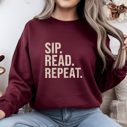 Person wearing a maroon sweatshirt with 'Sip. Read. Repeat.' text, sitting indoors.
